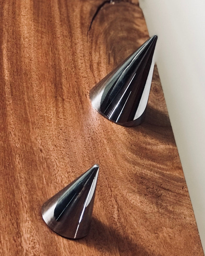 Three metallic cone-shaped objects on a wooden surface