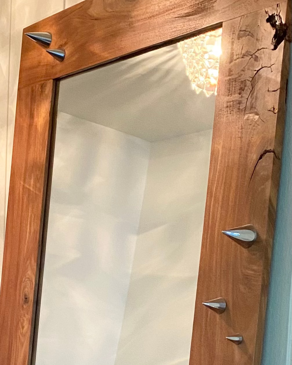Wooden-framed mirror with decorative elements on a wall.
