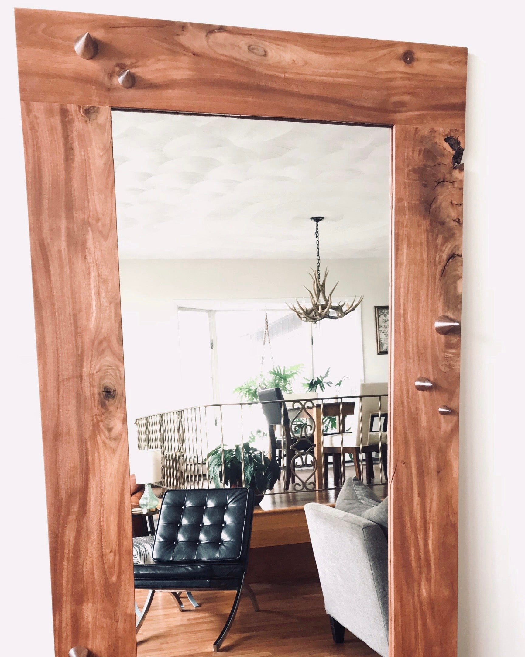 Wooden mirror with rustic frame reflecting a room with furniture.