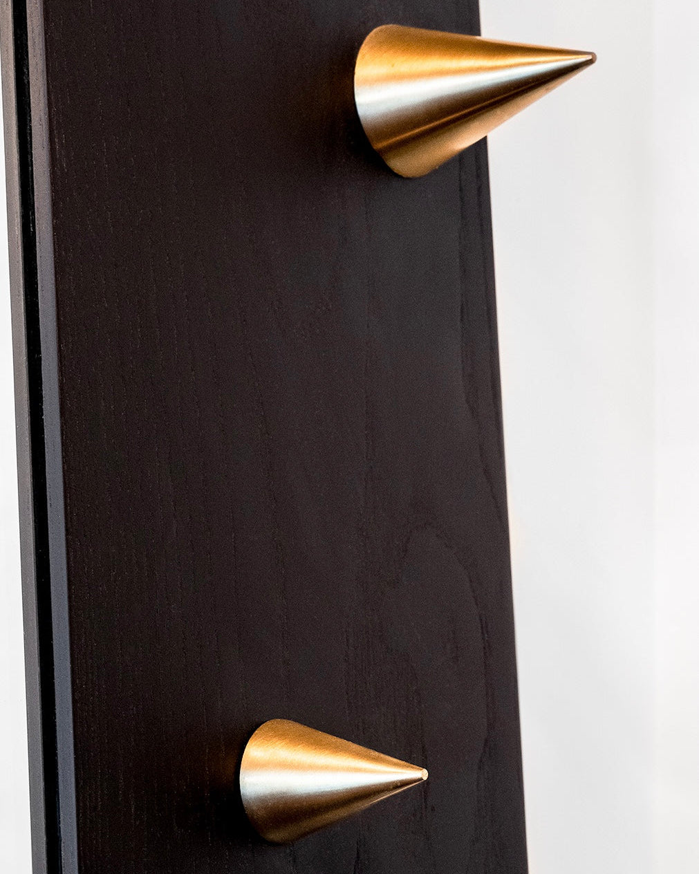Black door with gold spike-style handles on a white background